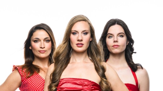 Drei Frauen stehen nebeneinander udn tragen rote Kleider. Der Hintergrund ist weiß.