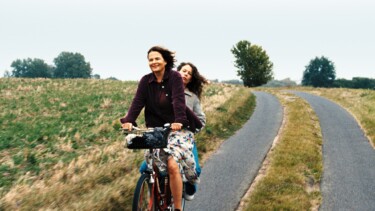Zwei Frauen auf einem Fahrrad auf einem Feldweg