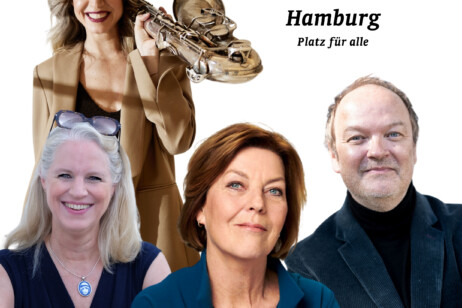 Drei Personen stehen nebeneinander, die linke trägt eine schwarze Bluse und eine silberne Halskette, die mittlere hat braune Haare und trägt ein braunes Sakko, die rechte Person trägt ein dunkles Sakko und ein schwarzes Hemd.