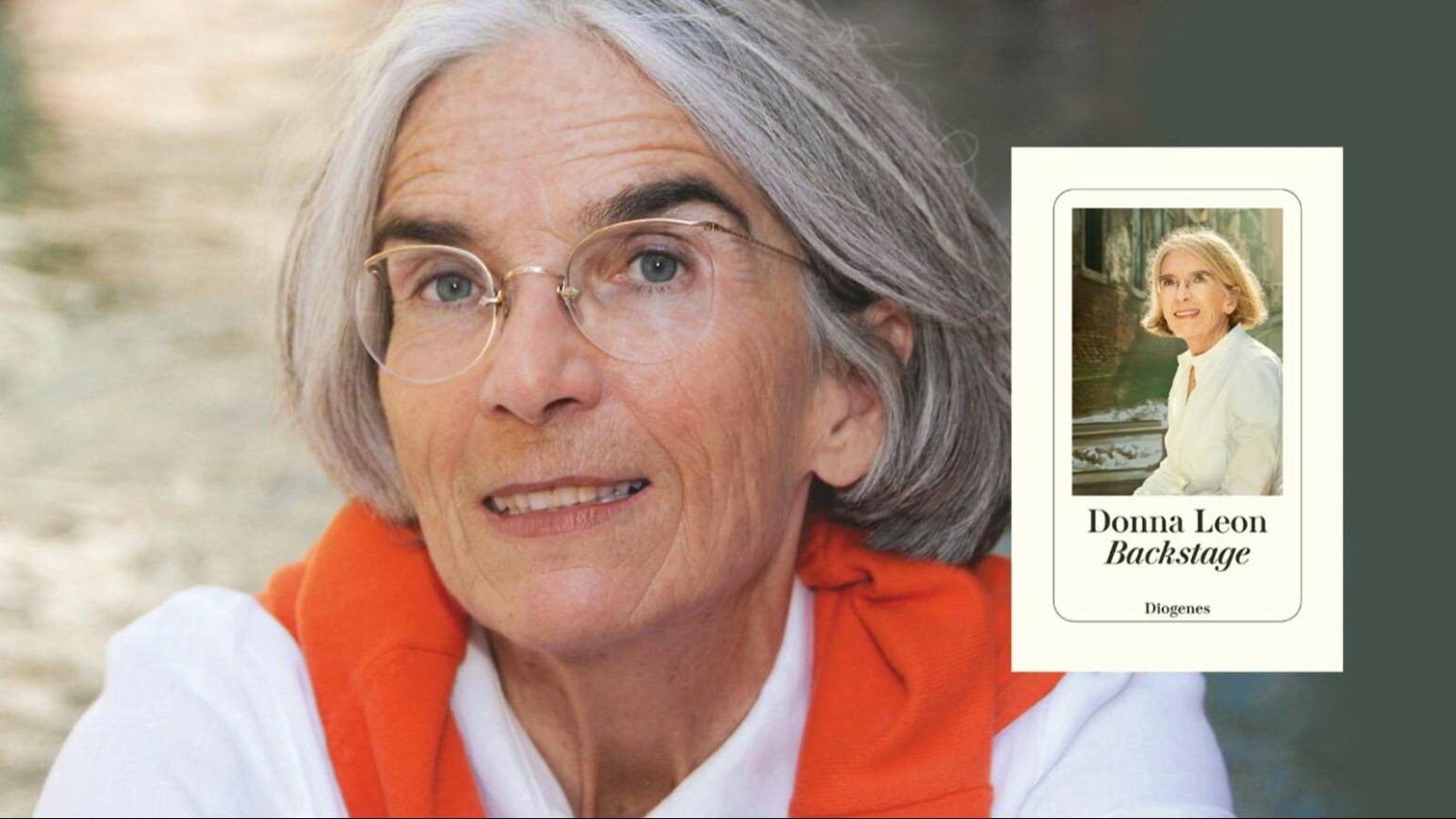 Ältere Person mit kurzen grauen Haaren, trägt weißen Pullover und orangenes Kleidungsstück um die Schultern gelegt.