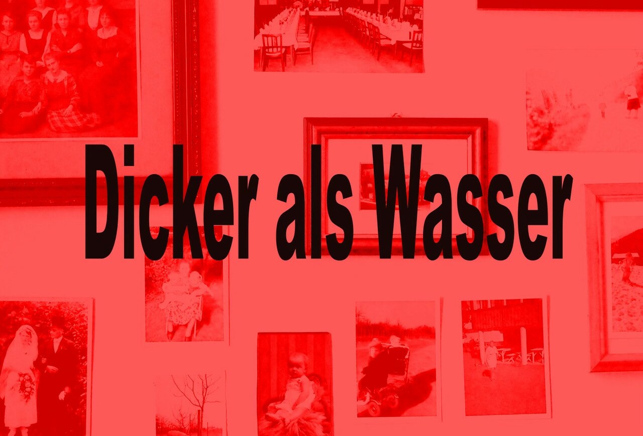 Wand mit mehreren gerahmten Schwarz-Weiß-Fotografien und dem Text 'Dicker als Wasser' in großer schwarzer Schrift.