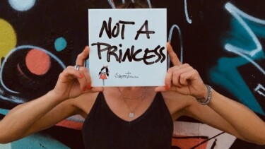 Person die ein Schild vor ihr Gesicht hält "Not A Princess"
