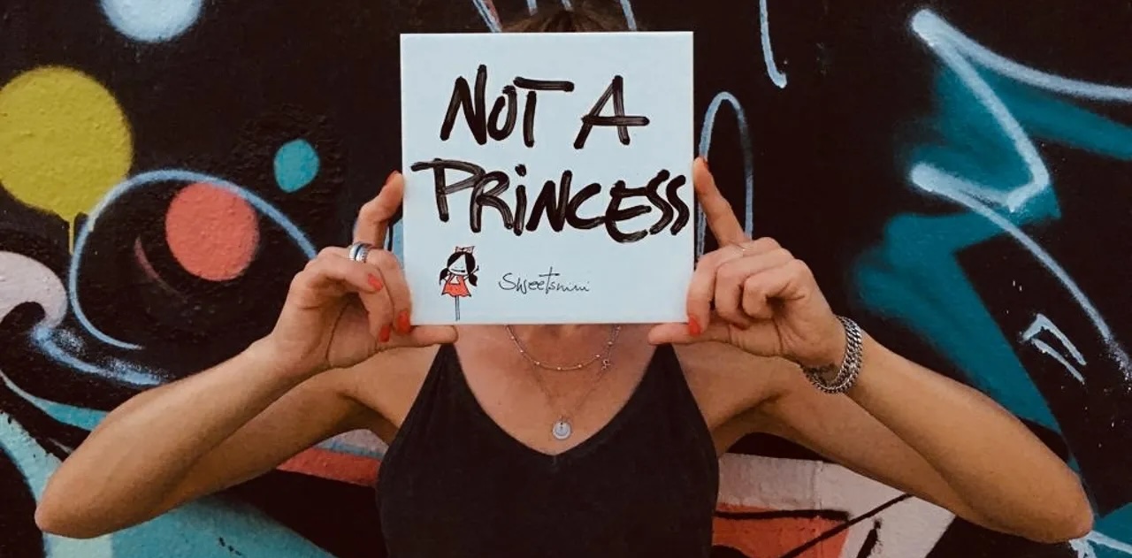 Person die ein Schild vor ihr Gesicht hält "Not A Princess"