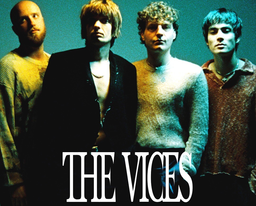 Die Band The Vices besteht aus vier Männern. Alle stehen nebeneinander in einem grünblauen Licht.