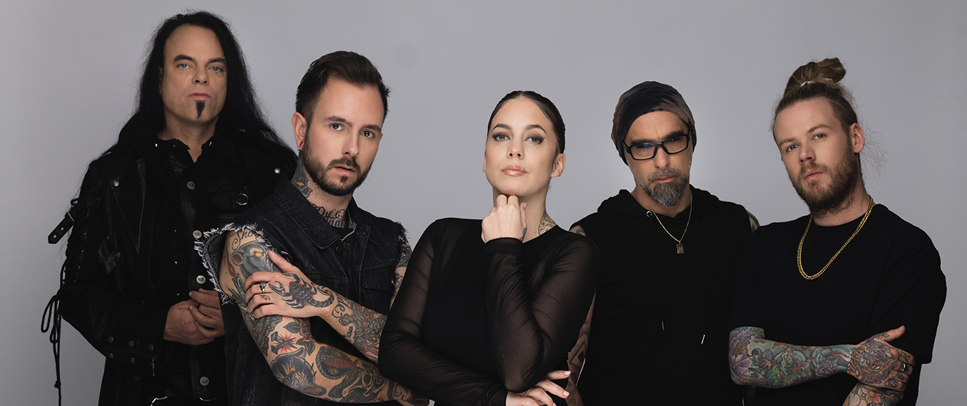 Fünf Personen in dunkler Kleidung, einige mit sichtbaren Tattoos an Armen, vor neutralem Hintergrund.