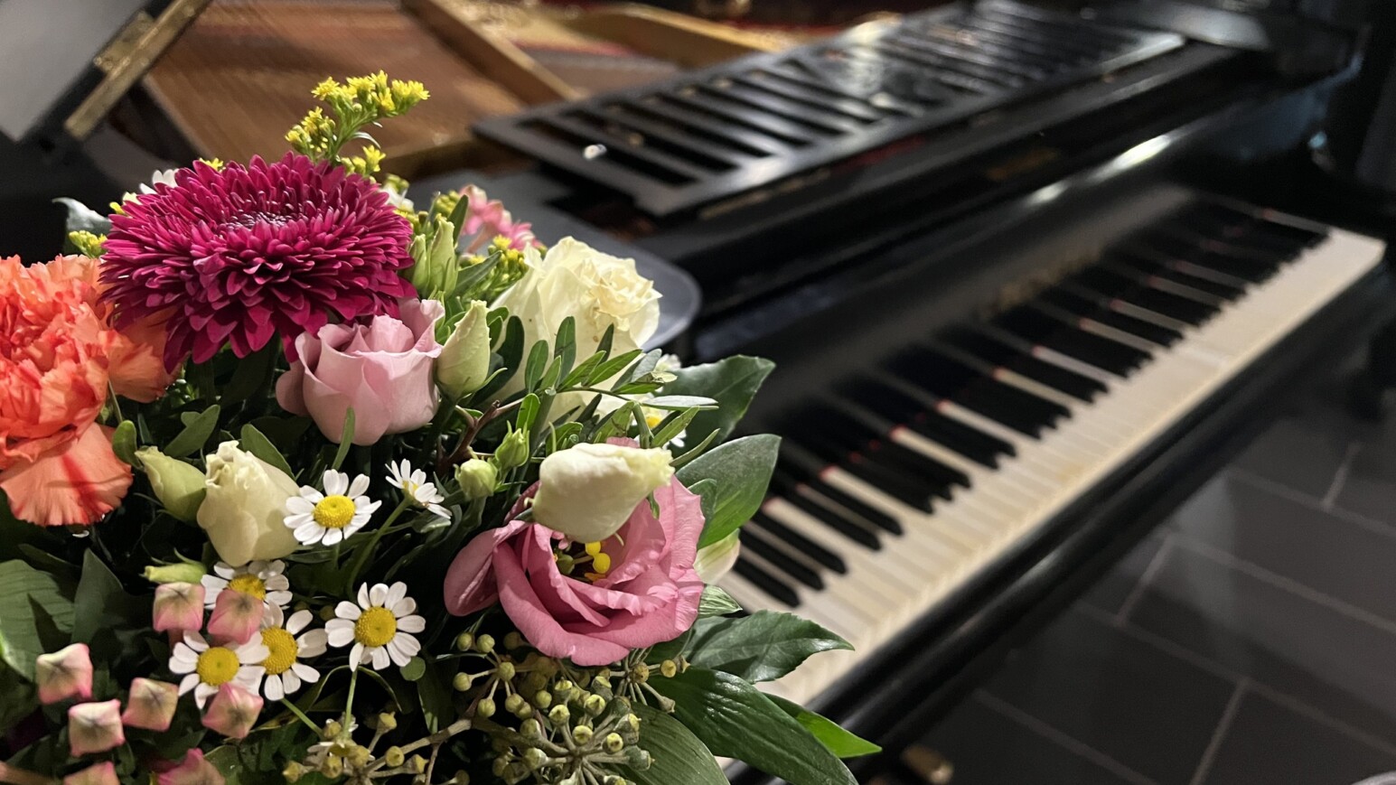Ein Klavier mit einem Blumenstrauß daneben