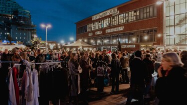 Menschenmenge vor der Rindermarkthalle mit beleuchteten Ständen und Gebäuden bei Abenddämmerung