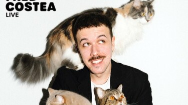 Person in schwarzem Sakko hält zwei Katzen, eine weitere Katze sitzt auf der Schulter. Text 'FRED COSTEA LIVE' oben links.