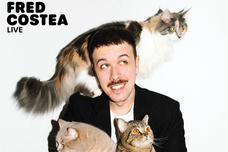 Person in schwarzem Sakko hält zwei Katzen, eine weitere Katze sitzt auf der Schulter. Text 'FRED COSTEA LIVE' oben links.