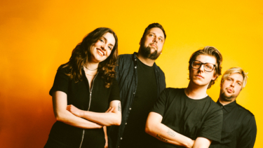 Vier Personen vor gelbem Hintergrund