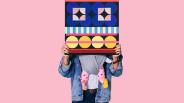 Person vor einer rosa Wand die ein Quadrat hält