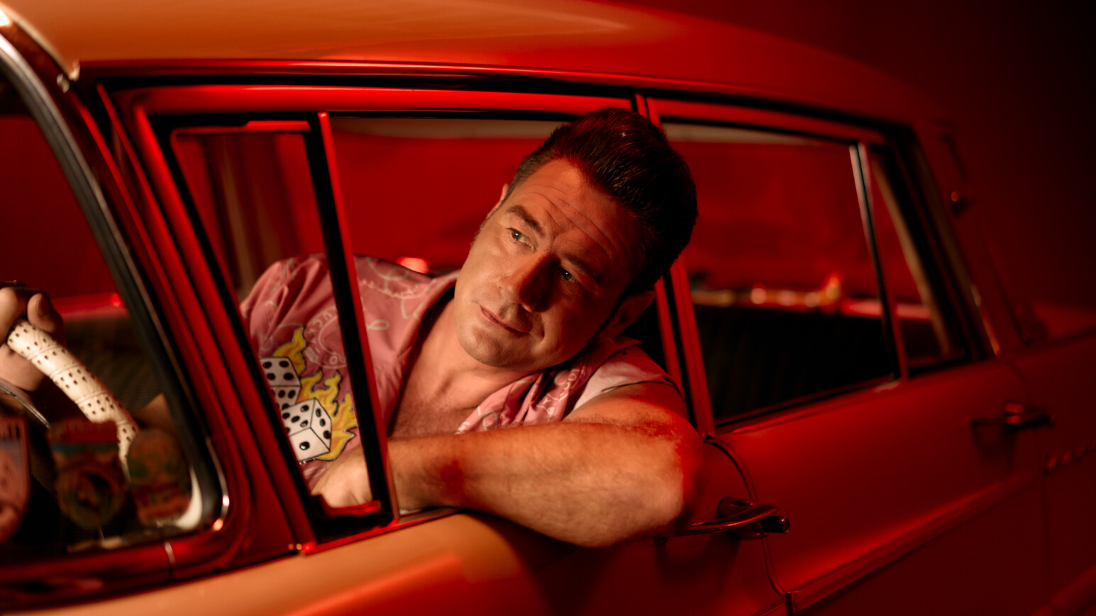 Deutscher Rock'n'Roll Musiker Dick Brave am Steuer eines roten Autos