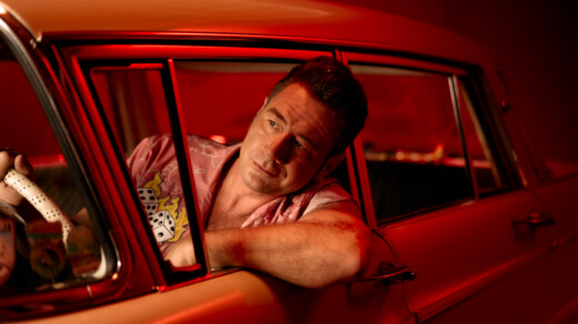 Deutscher Rock'n'Roll Musiker Dick Brave am Steuer eines roten Autos