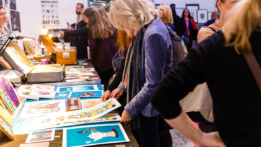 Person stöbert auf einem Kunstmarkt nach Prints