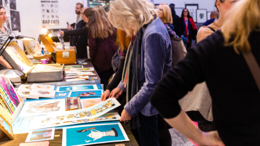 Person stöbert auf einem Kunstmarkt nach Prints