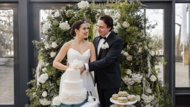 Nach einem alten Brauch hat die Person „Die Hosen in der Beziehung an“, die beim Hochzeitstorten anschnitt die Hand in Top hat