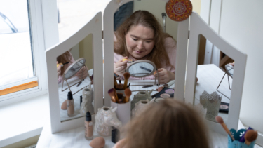 Eine Frau schminkt sich am Schminktisch vor dem Spiegel