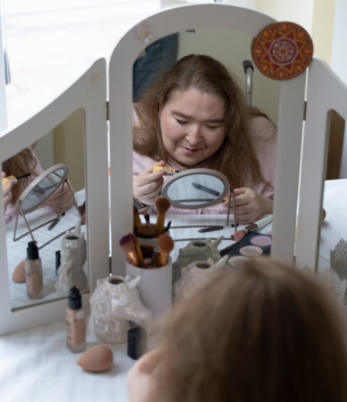 Eine Frau schminkt sich am Schminktisch vor dem Spiegel