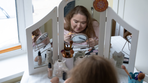 Eine Frau schminkt sich am Schminktisch vor dem Spiegel