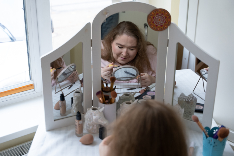 Eine Frau schminkt sich am Schminktisch vor dem Spiegel