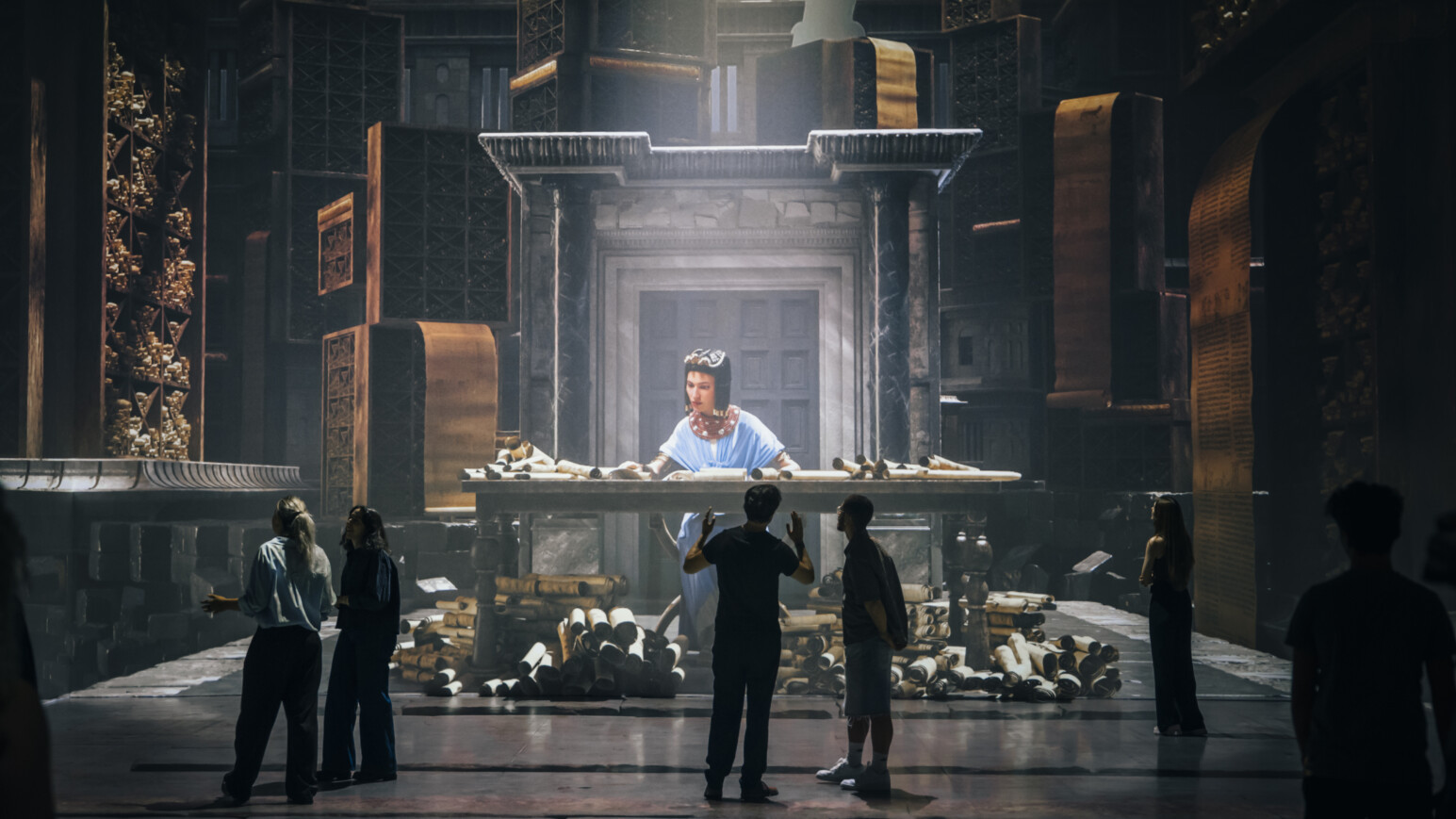 Menschen stehen vor einer Projektion Kleopatras in einem großen Ausstellungsraum