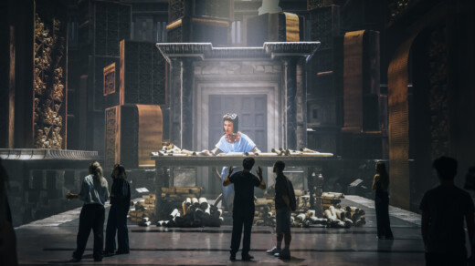 Menschen stehen vor einer Projektion Kleopatras in einem großen Ausstellungsraum