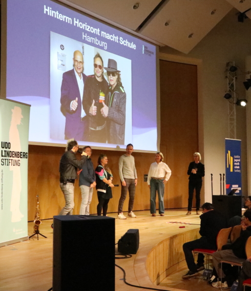 Auf der Bühne: Die Künstlerische Leitung des Originalmusicals und des Projektes Noah Fischer (links) und Elisabeth Engstler (rechts) mit Vertretern der beiden Gewinner-Schulen (Mitte), der ATW Hamburg und des Gymnasium Farmsen