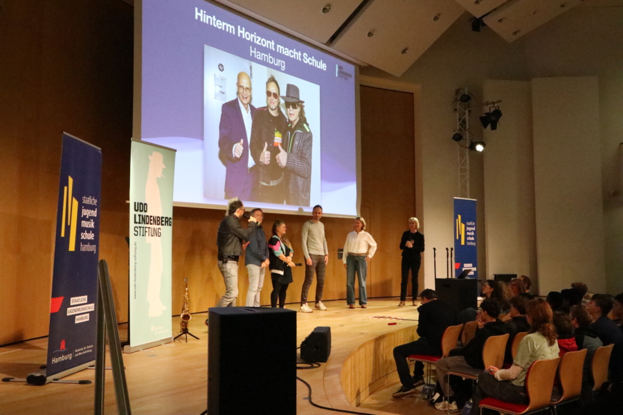 Auf der Bühne: Die Künstlerische Leitung des Originalmusicals und des Projektes Noah Fischer (links) und Elisabeth Engstler (rechts) mit Vertretern der beiden Gewinner-Schulen (Mitte), der ATW Hamburg und des Gymnasium Farmsen